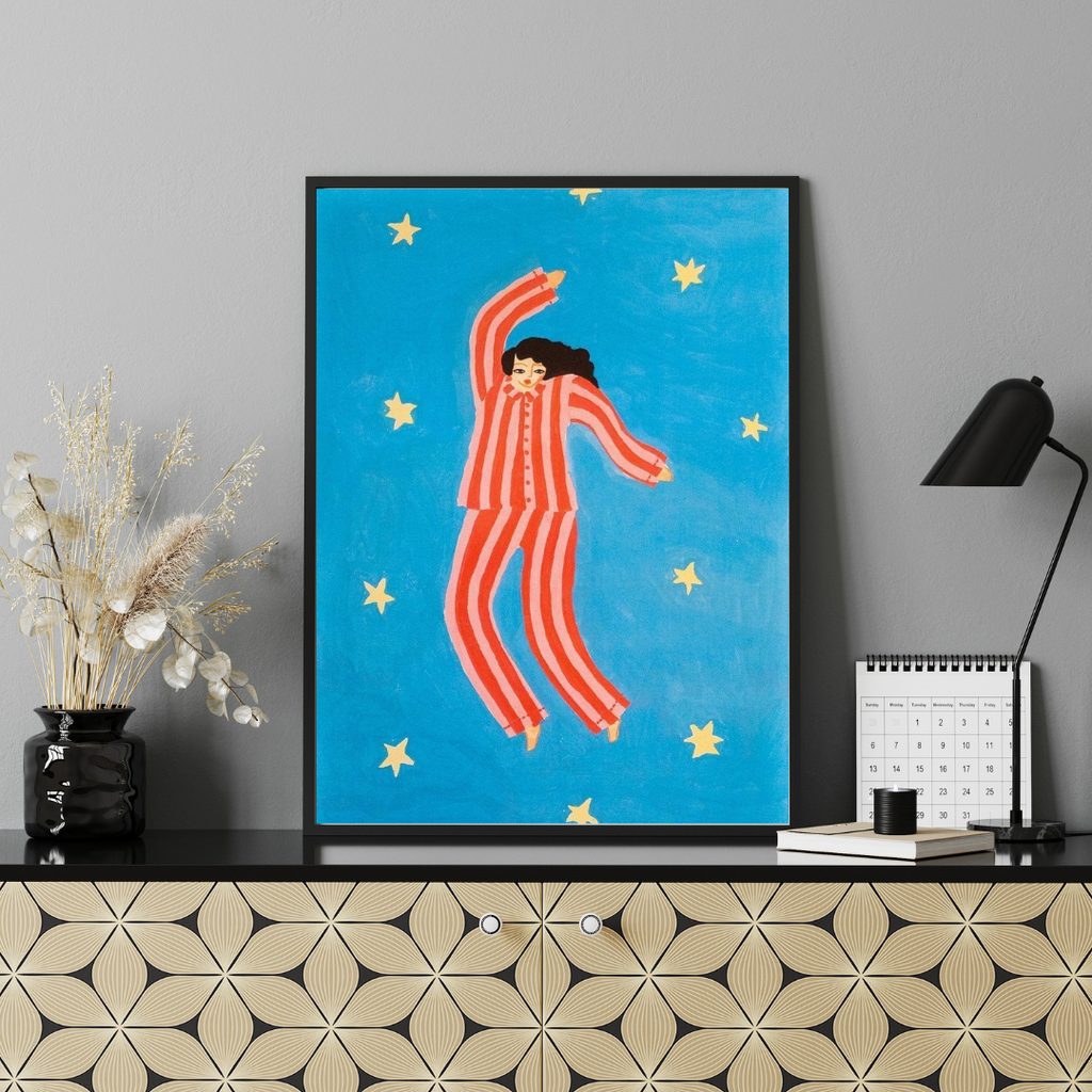 Framed artwork of a person in a red outfit against a blue background with stars on a shelf.